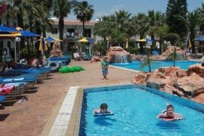 Территория отеля  Loutsiana II Deluxe Apartments представляет собой цветущий сад с большим бассейном, теннисным кортом и детской игровой площадкой